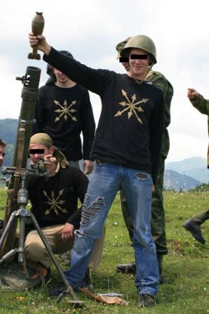 Young men operating a mortar wearing t-shirst with an eight-rayed motif.