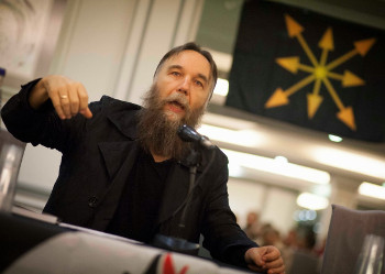 Dugin giving a talk before a chaos star banner.